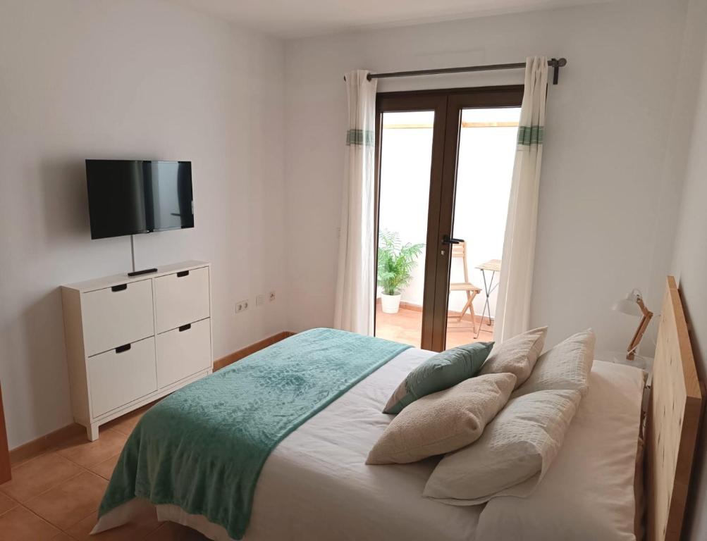 um quarto com uma cama com almofadas e uma televisão em Casa Calderetas em San Bartolomé