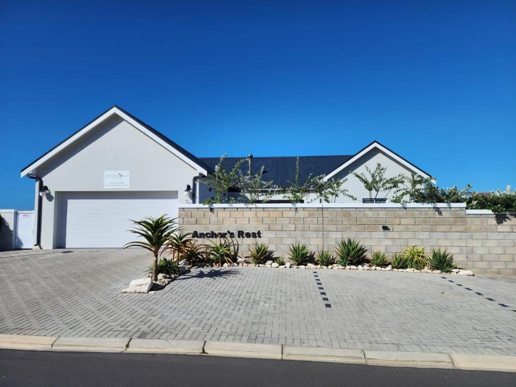 una casa blanca con una puerta de garaje blanca y algunas plantas en Anchor's Rest, en Yzerfontein