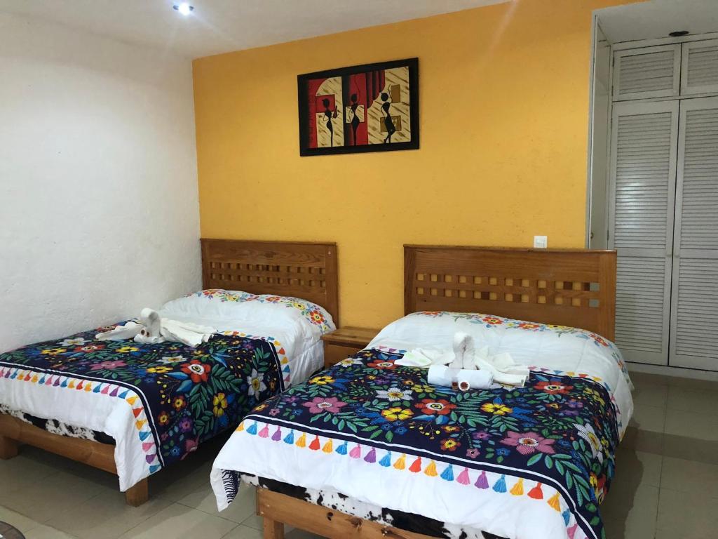 1 dormitorio con 2 camas y una foto en la pared en Los Robles, en Tepoztlán