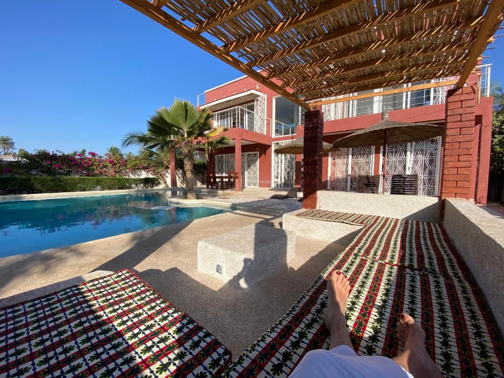 a person laying on a rug next to a swimming pool at Villa avec piscine entre plage et Siné Saloum in Palmarin