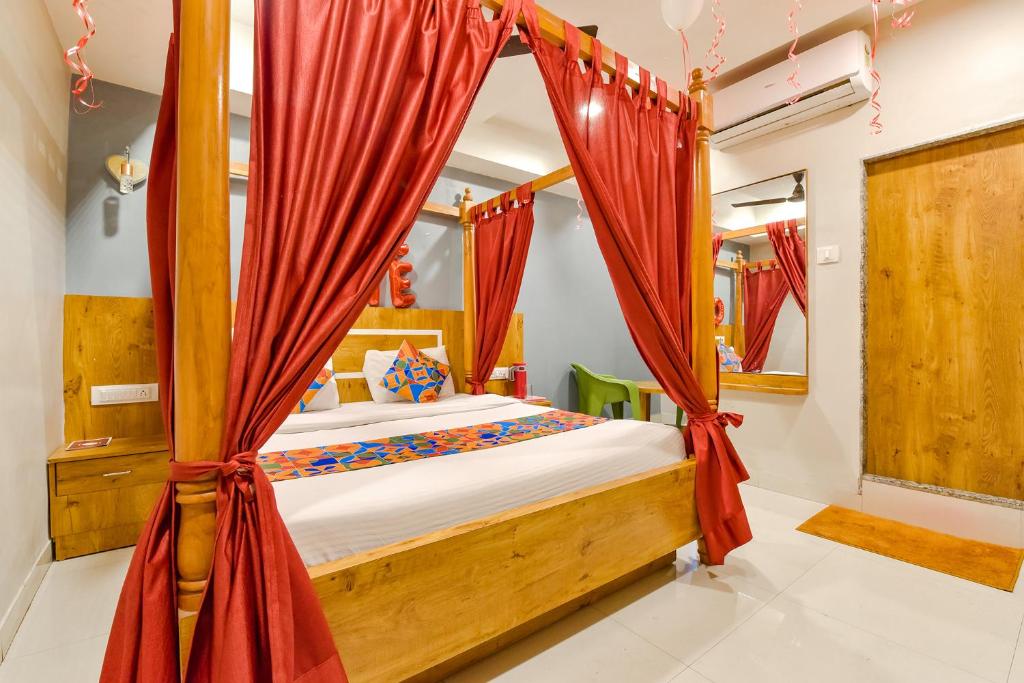 a bedroom with a canopy bed with red curtains at FabHotel Apollo in Naroda