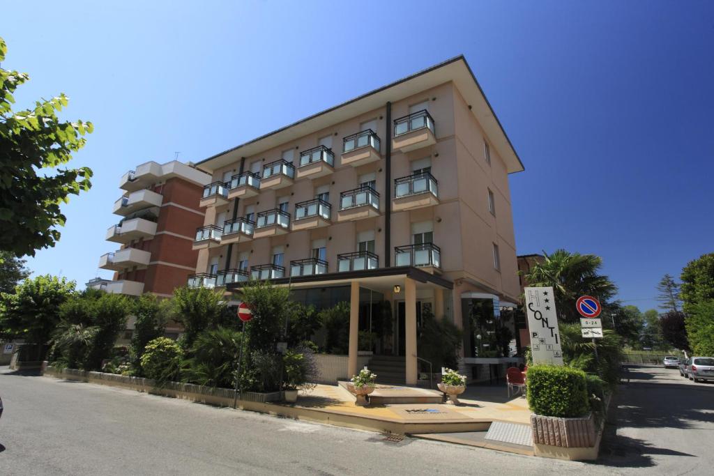 un grand bâtiment au bord d'une rue dans l'établissement Hotel Conti, à Rimini