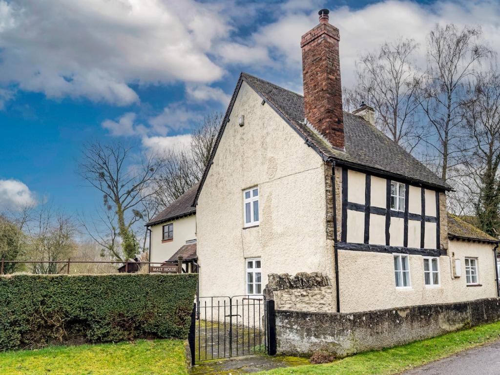 an old stone house with a chimney and a gate at Pass the Keys Malt House With Hot Tub Stunning Tudor Cottage in Craven Arms