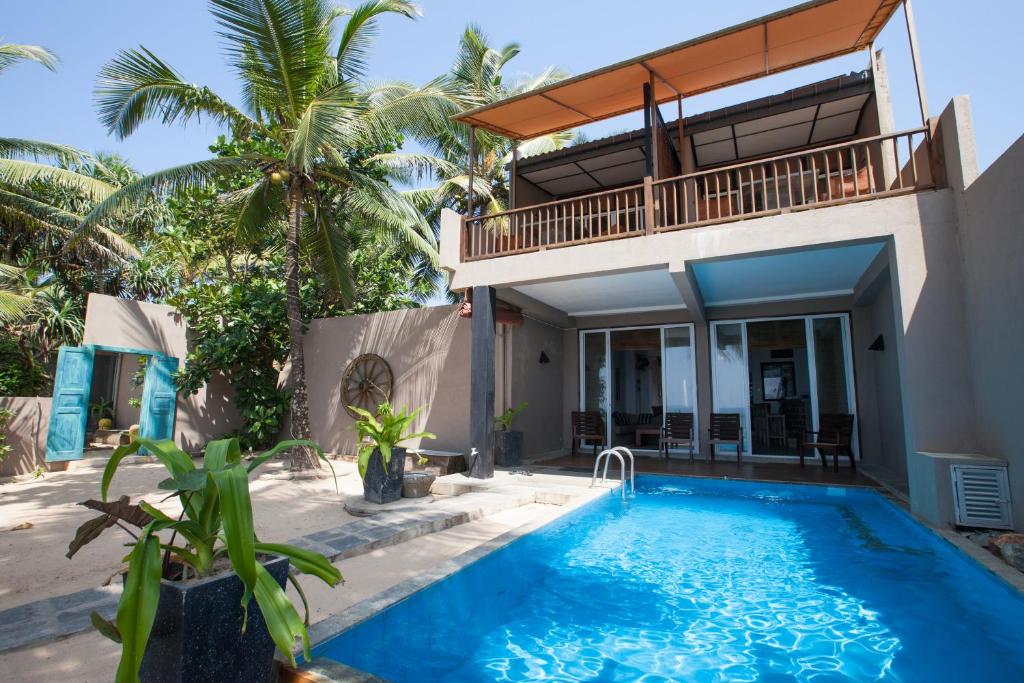 a villa with a swimming pool and a house at Hikks Villa in Hikkaduwa