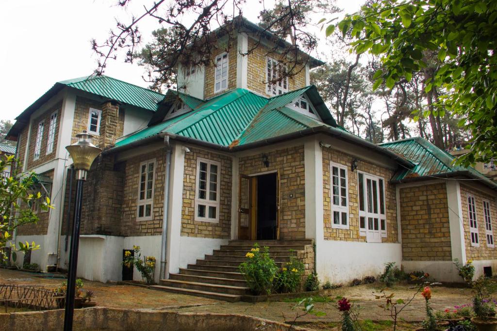 une maison ancienne avec un toit vert et des escaliers dans l'établissement KEN & TWILL, à Shillong