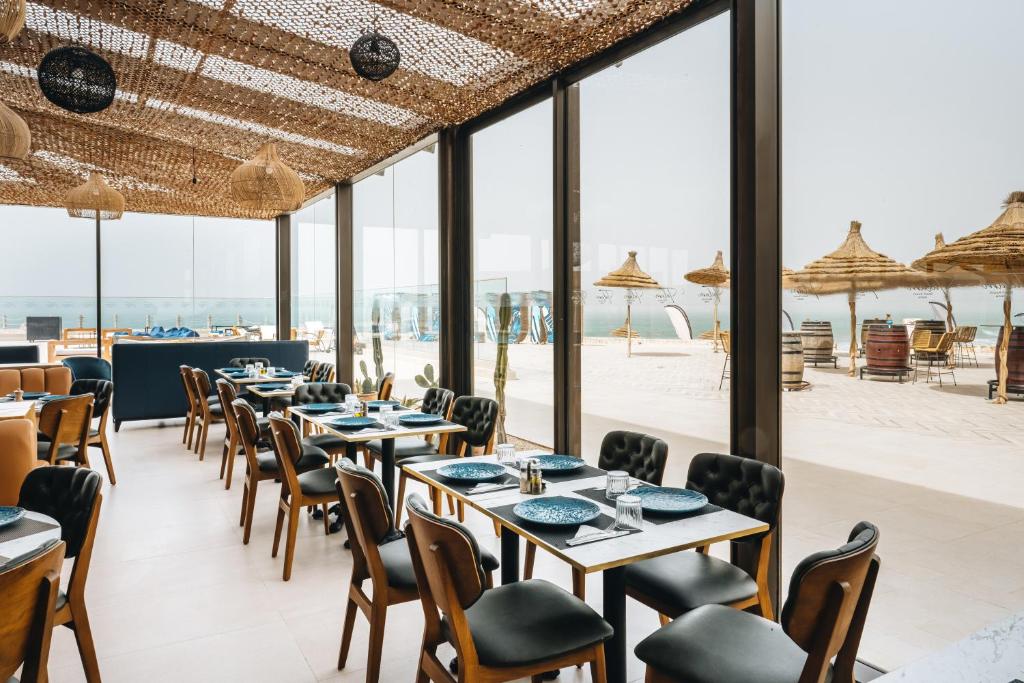 a dining room with tables and chairs and a beach at Tulum Beach Resort Dakhla in Dakhla