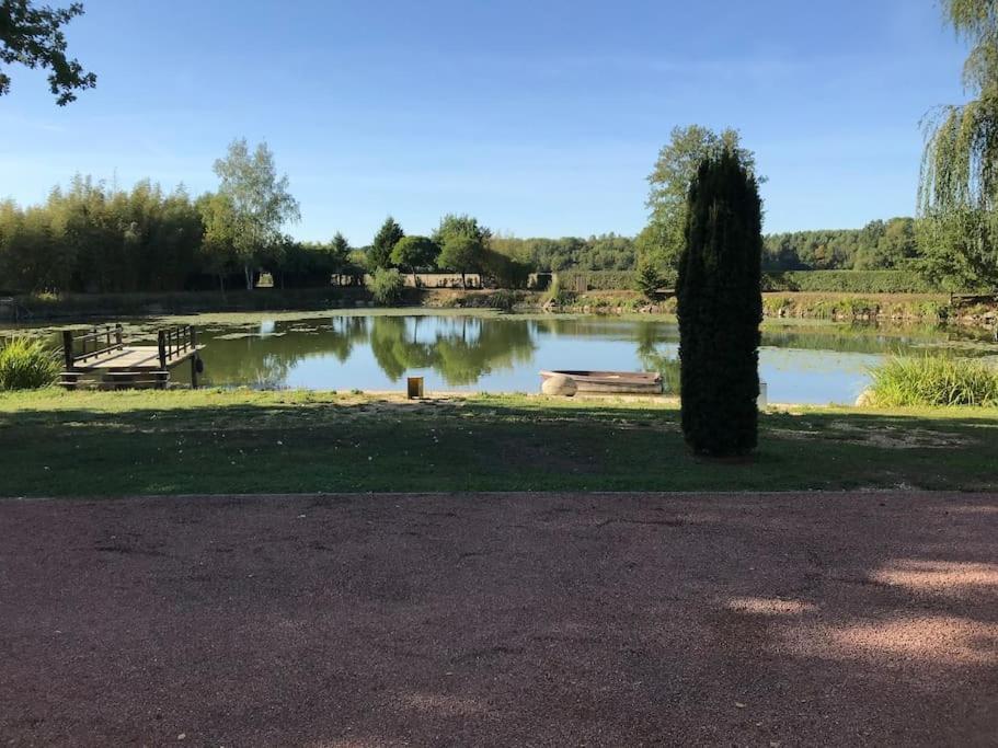 um parque com um lago com um banco e uma árvore em L’Eden de JoLéo : votre cocon d’amour em Perthes