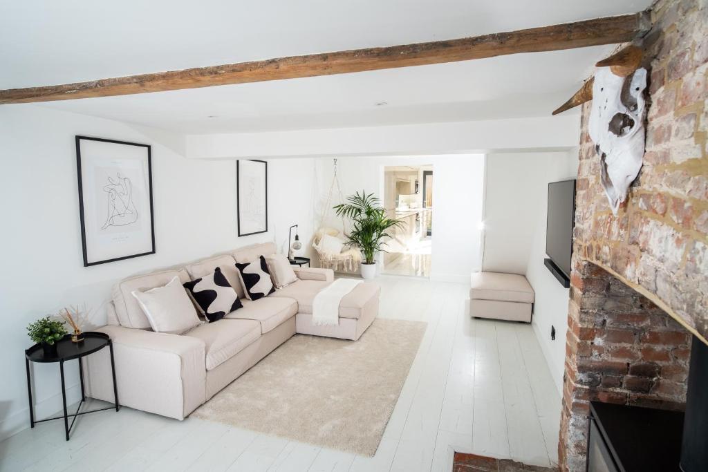 a living room with white furniture and a brick wall at The Scandi Cottage in Theydon Bois