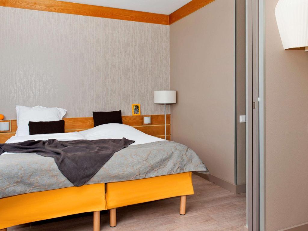 パリにあるアパートホテル アダージョ アパートホテル パリ XVのベッドルーム1室(大型ベッド1台、木製ヘッドボード付)