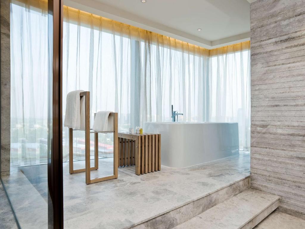 a bathroom with a tub and a large window at East Beijing in Beijing
