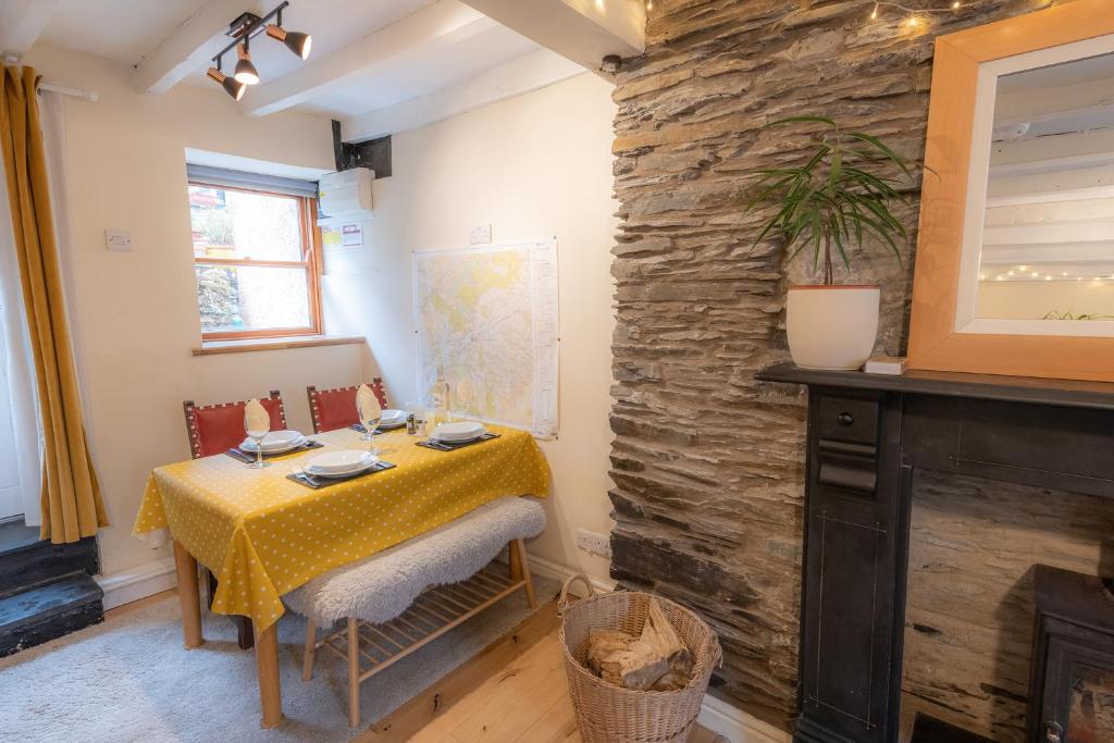 a dining room with a table and a stone wall at Tri deg un, cottage for 2 adults and 2 children in Machynlleth