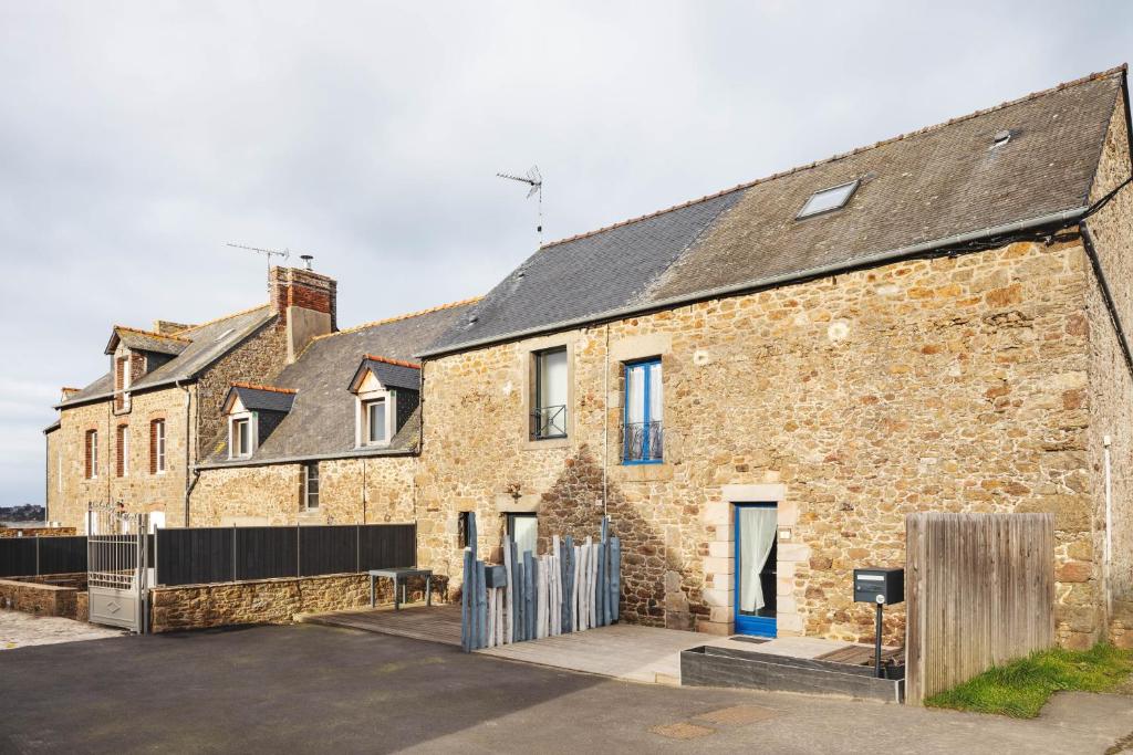an old brick building with a fence in front of it at Les Petits Matelots - Maison proche plage in Saint-Coulomb