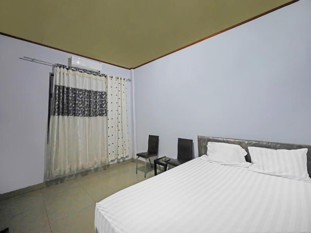 a bedroom with a large white bed and two chairs at OYO 92230 Penginapan Metro Parepare in Parepare