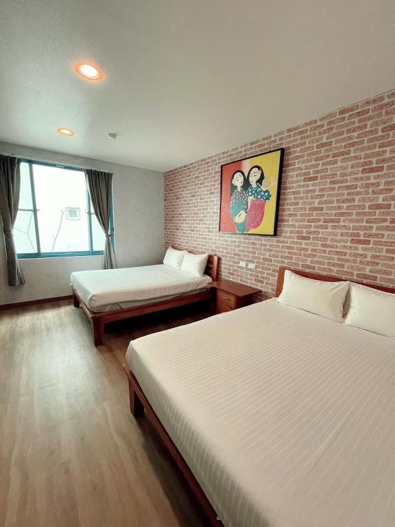 a bedroom with two beds and a brick wall at Blue Sea Inn in Eluan