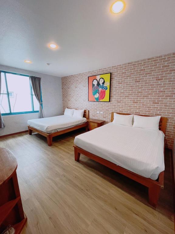 a bedroom with two beds and a brick wall at Blue Sea Inn in Eluan
