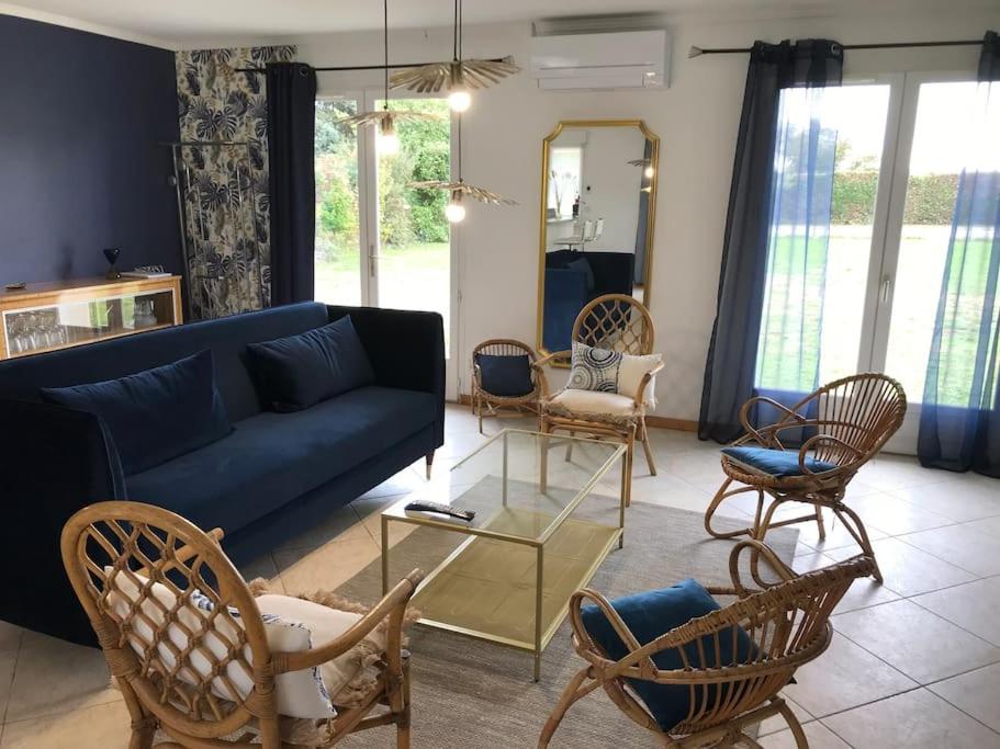 ein Wohnzimmer mit einem blauen Sofa und Stühlen in der Unterkunft MAISON CHAMPAGNE, charmante maison au calme avec beau terrain in Saint-Germain