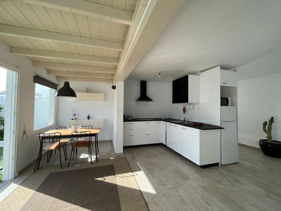 a kitchen with white cabinets and a table with chairs at Loft en zona rural de Lanzarote in Conil