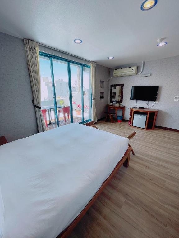 a bedroom with a large white bed and a large window at Blue Sea Inn in Eluan