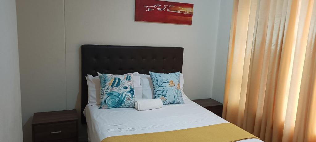 um quarto com uma cama com uma cabeceira e almofadas pretas em myStay Sandton em Joanesburgo