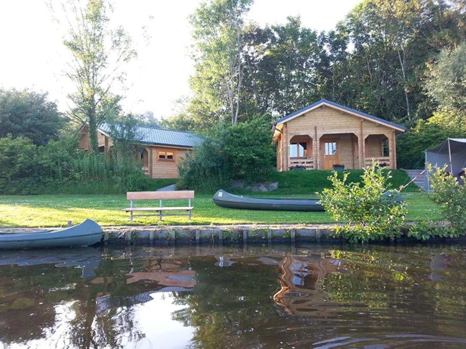 een blokhut naast een meer met een bank bij Camping 't Ol Gat in Zoutkamp