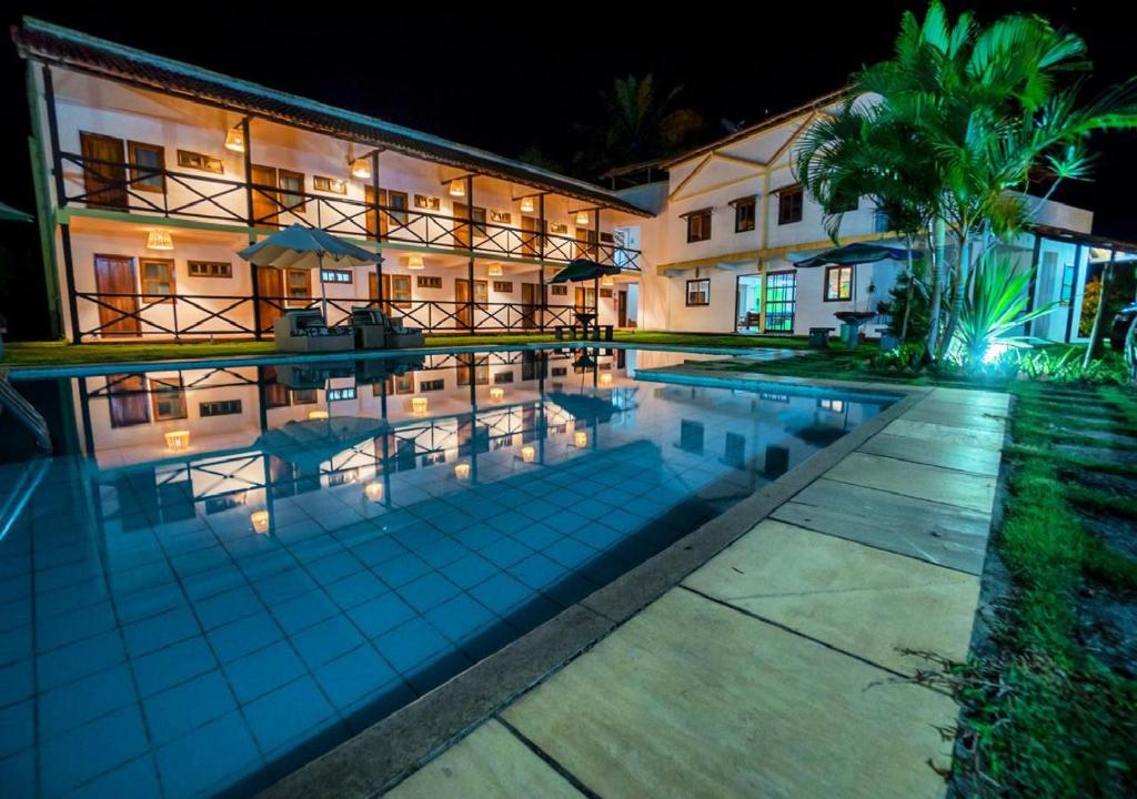 a swimming pool in front of a building at night at Pousada Casarão de Itaúnas in Itaúnas