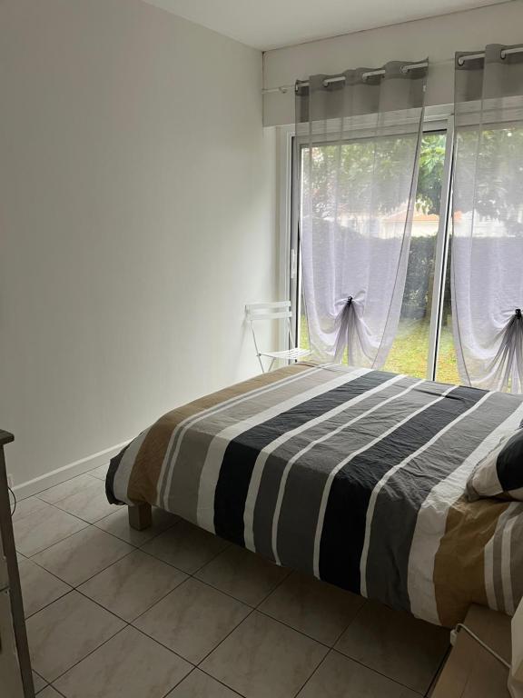 a bedroom with a bed and a large window at Logement plein centre royan in Royan