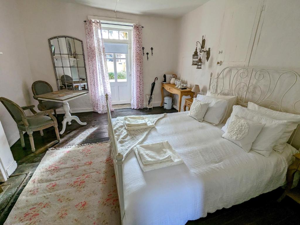 a bedroom with a white bed and a table and a window at Sous le Chateau in Jumilhac-le-Grand
