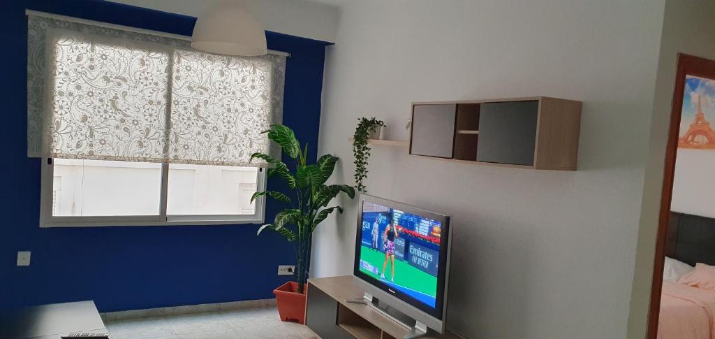 a living room with a tv and a blue wall at Apartamento Ciudad de las Ciencias 3 in Valencia