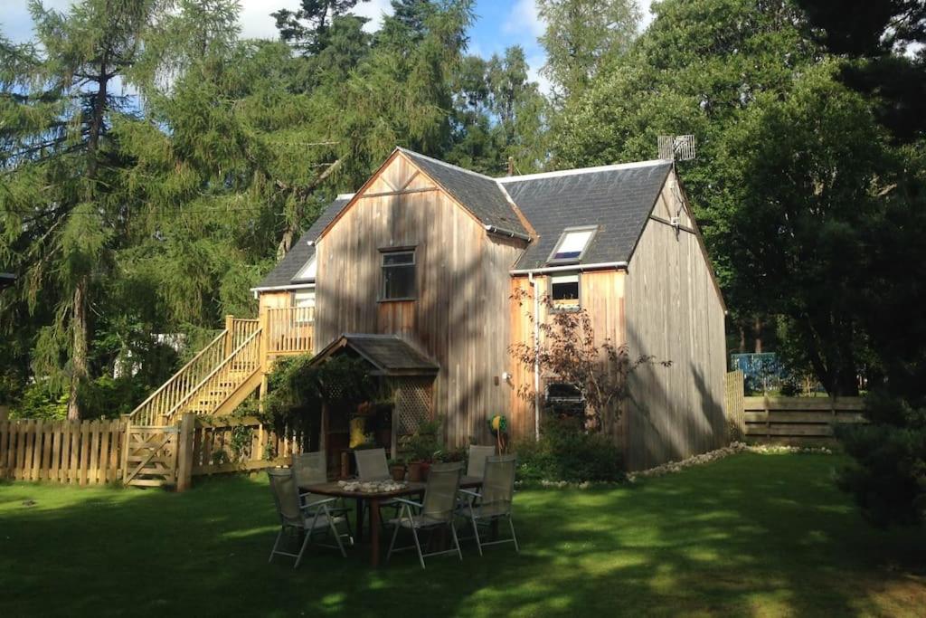 a barn with a table and chairs in a yard at The Beeches Studio, Highlands of Scotland in Newtonmore