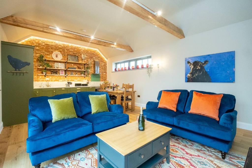 a living room with two blue couches and a table at Alde Bay Farm - Coral Cottage in Aldeburgh