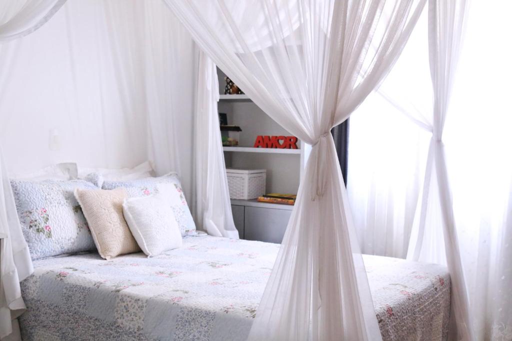 1 dormitorio con cama blanca con dosel y ventana en Apt no Alto de Pinheiros, en São Paulo