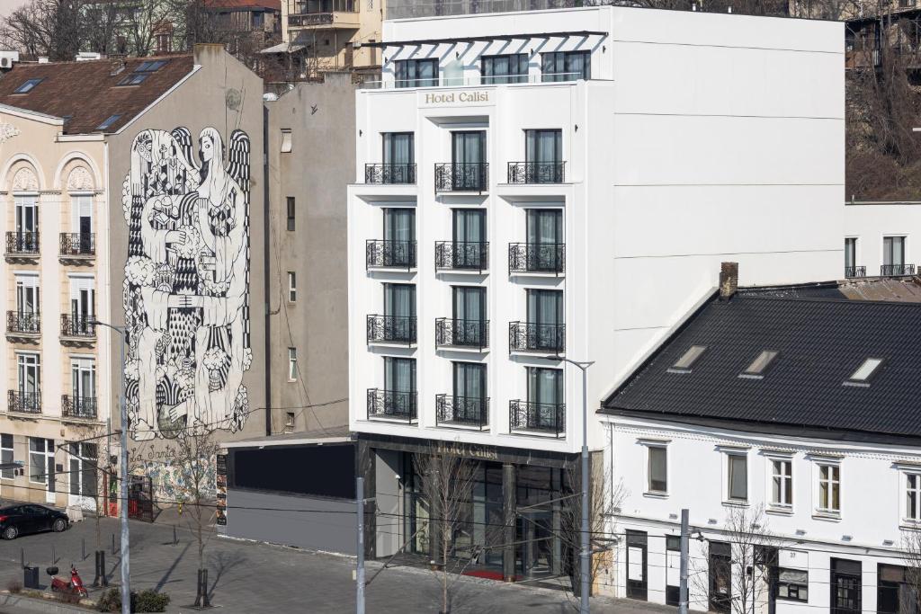 un edificio bianco con un murale sul lato di Calisi Hotel a Belgrado