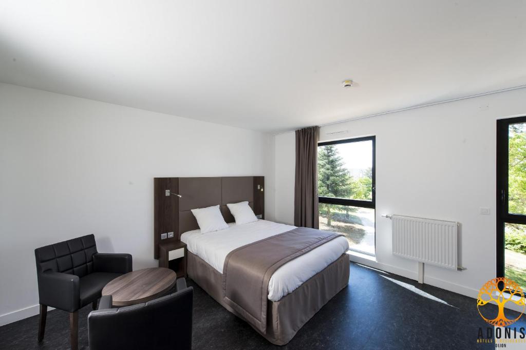 a bedroom with a bed and a chair and a window at Adonis Dijon Maison Internationale in Dijon
