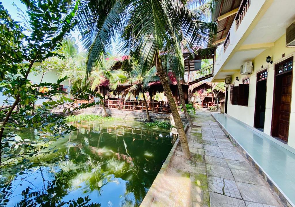 a pool of water in front of a building with palm trees at Khách sạn Sao Mai in Ben Tre