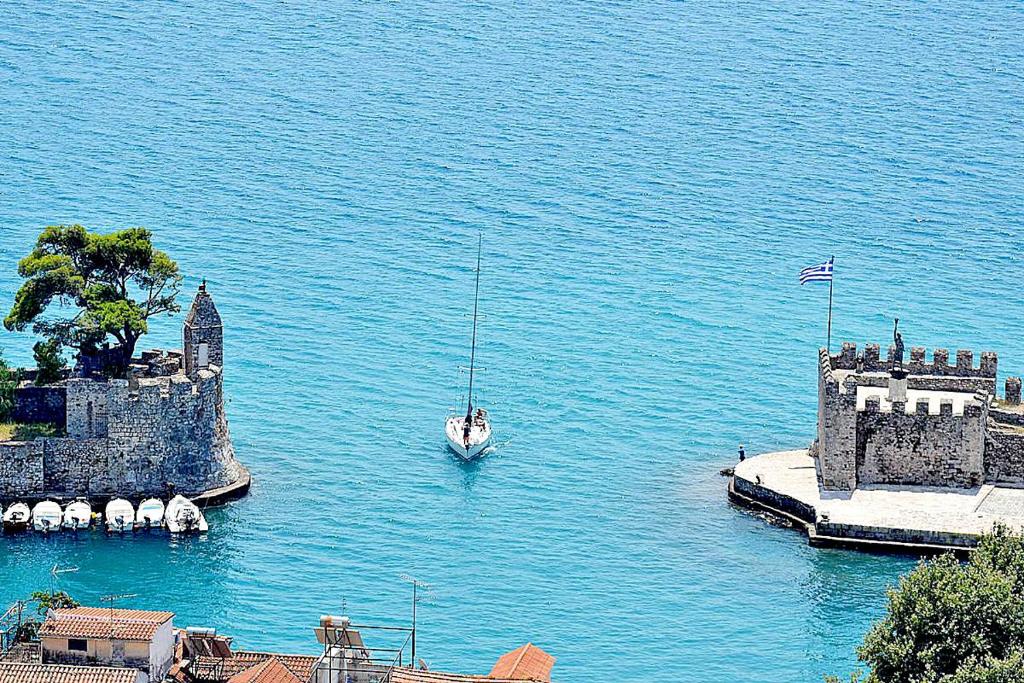 a boat in the water next to a castle at NAFPAKTOS-luxury suite in Nafpaktos