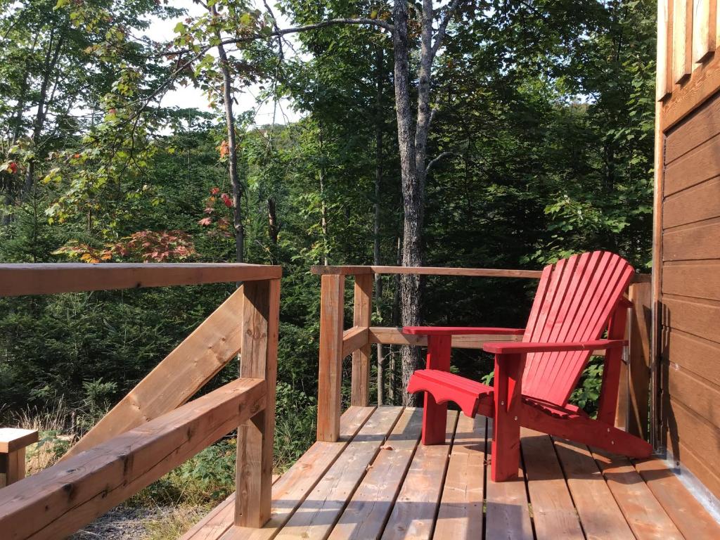 a red chair sitting on the deck of a cabin at Loft Nature Laurentides in Val-des-Lacs