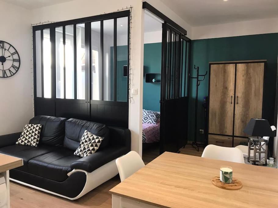 un salon avec un canapé noir et une table dans l'établissement Studio le p'tit Wims à 350 m de la plage, à Wimereux