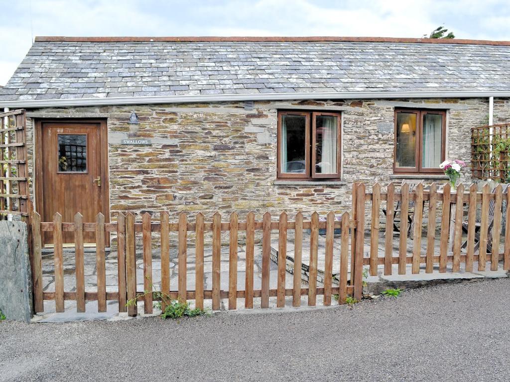 a house with a wooden fence in front of it at Swallows in Delabole