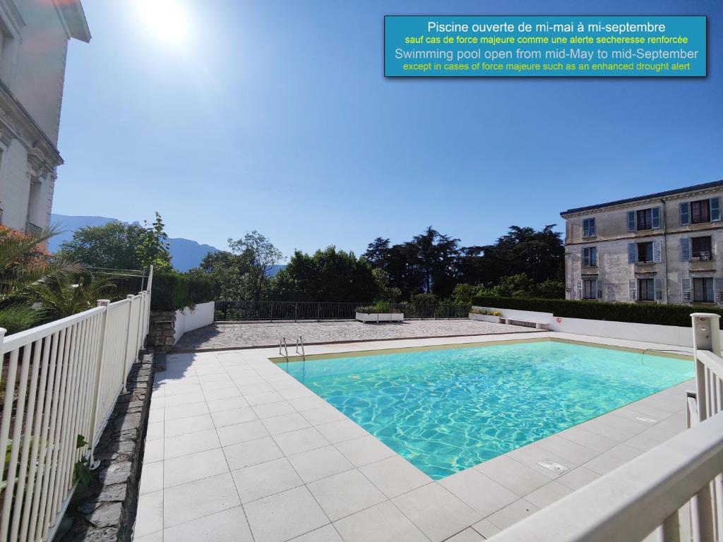 basen z białym płotem i budynek w obiekcie Grand studio 38m2 dans ancien palace avec piscine et place de parking privée w Aix-les-Bains