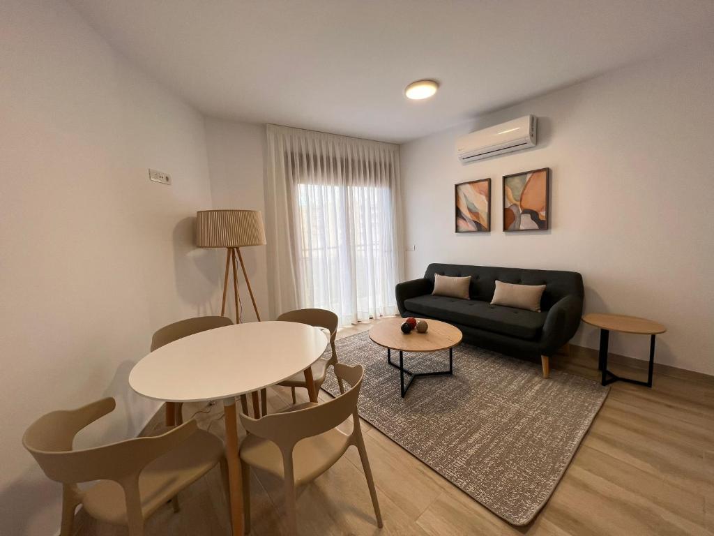 a living room with a couch and a table and chairs at Apartamentos Doña Emilia in Adeje