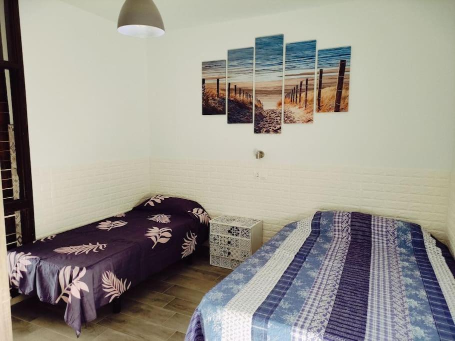 Costa del Silencio El Drago في طوستا ديل سيلونثيو: سريرين في غرفة بها لوحتين على الحائط
