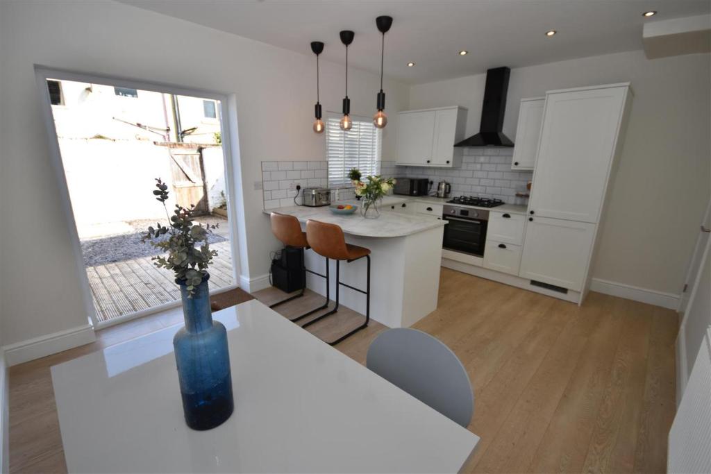 a kitchen with white cabinets and a table with chairs at 2 bedroom house in Hoylake - Golf Open in Hoylake