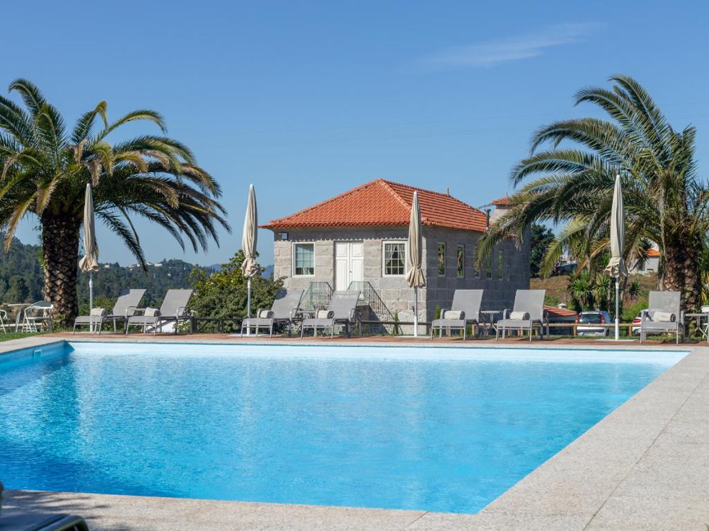 a swimming pool in front of a house with palm trees at Quinta de Carcavelos Natures Home in Amarante