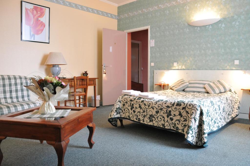 um quarto com uma cama, uma mesa e um sofá em Hôtel De Paris em Charleville-Mézières