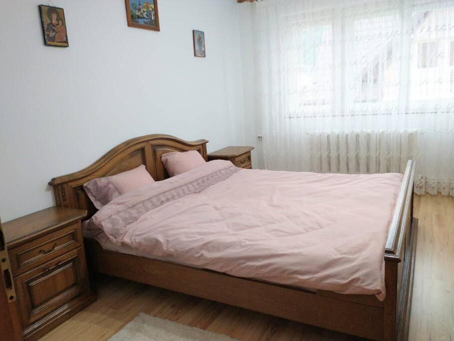 a bedroom with a bed with white sheets and a window at Casa Livia în inima Bucovinei in Gura Humorului