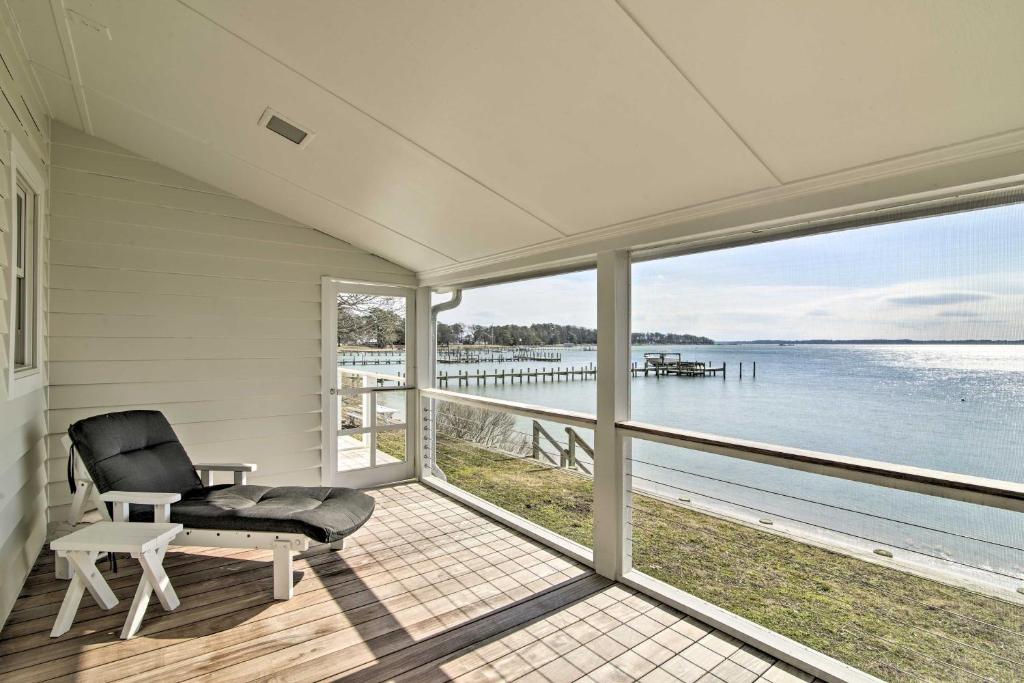 a chair on a porch with a view of the water at Bayside Deltaville Retreat with Beach and Bay Views! in Locklies