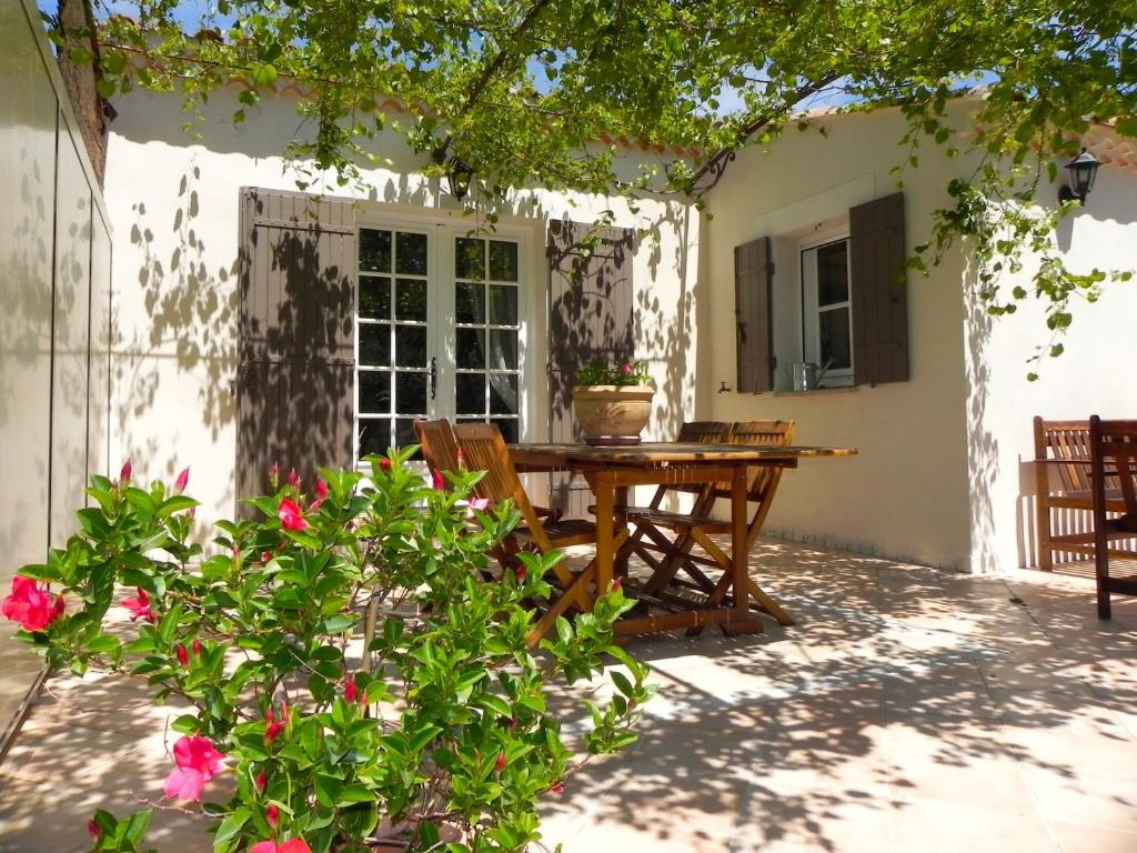 une terrasse avec une table et des fleurs devant une maison dans l'établissement Gite Chez Un Producteur de Fruits., à Boulbon