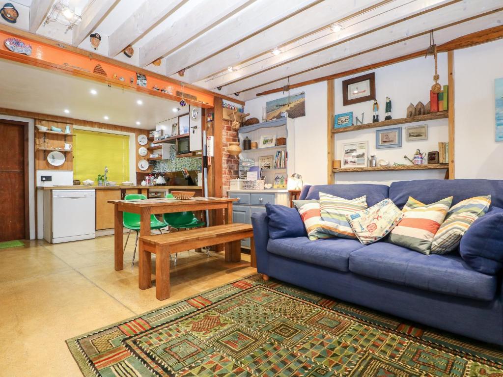 ein Wohnzimmer mit einem blauen Sofa und einer Küche in der Unterkunft Cowes View Cottage in Fareham