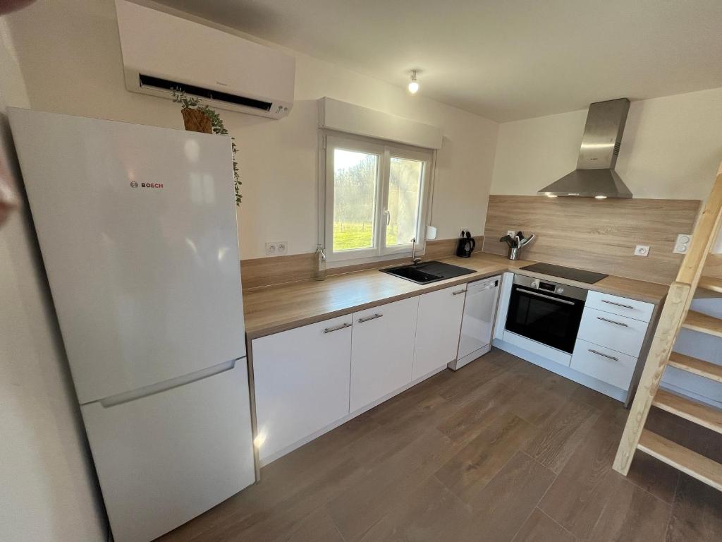 a kitchen with white cabinets and a white refrigerator at SCI BSA Magnifique maison au calme in Les Essards-Taignevaux