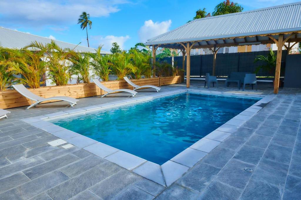 a swimming pool with chairs and a gazebo at LES VILLAS LOURYA MARIE-GALANTE in Grand-Bourg